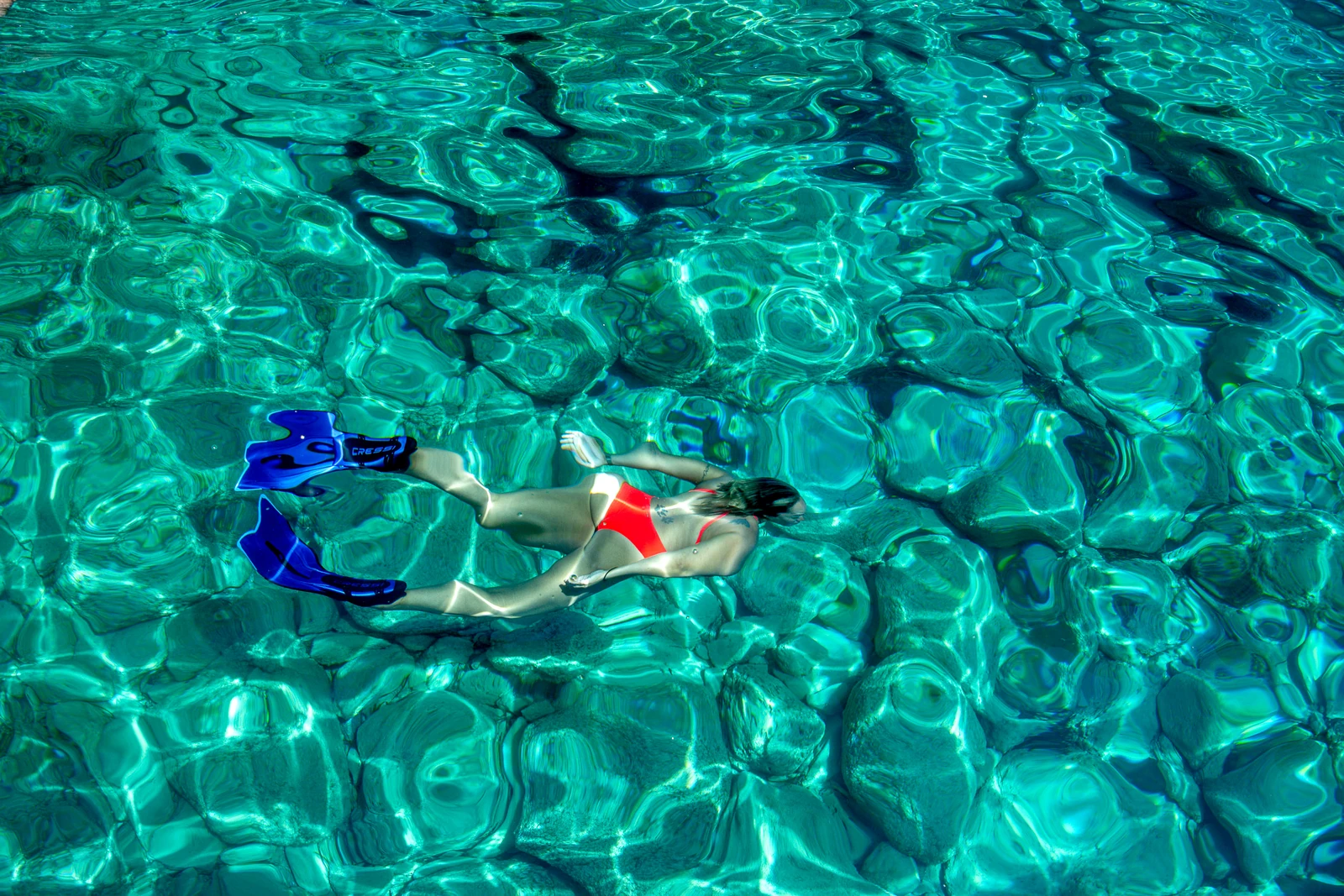 A swimmer floating above the rocks in clear turquoise water