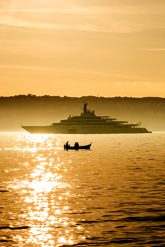 Yacht and small boat silhouetted on a golden sea at sunset